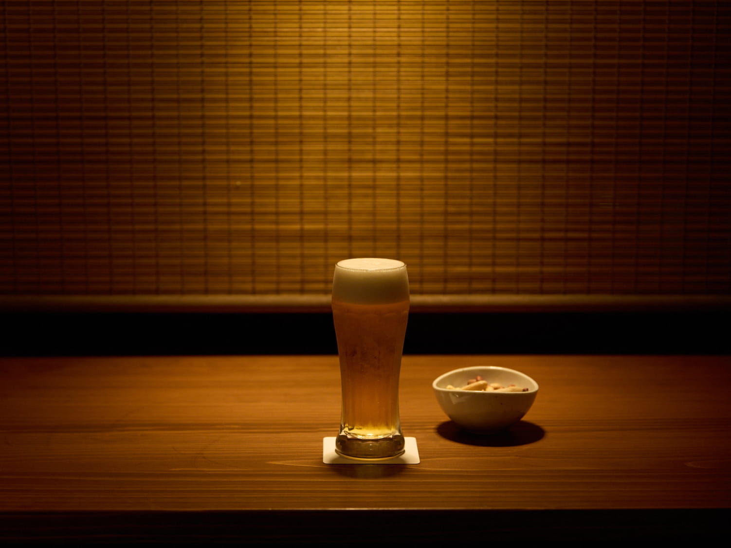 夜の榎屋茶房。テーブルに置いてあるビールとおつまみが一灯のライトに照らされている